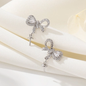 Macro view of silver bow jewelry finding with pavé zircons and heart stone for DIY