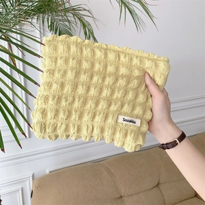 Close-up of a bright yellow bubble textured makeup bag held by hand in home setting