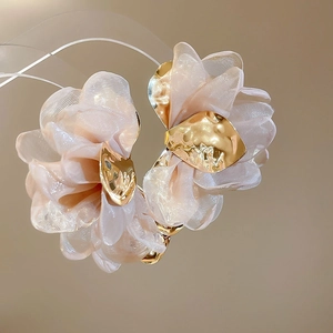 Detail of light pink chiffon flower hair claw with textured golden metal leaves