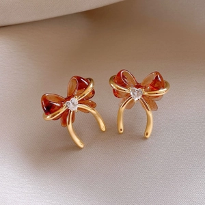Macro shot of retro bow earrings with amber resin and heart-shaped crystal center