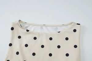 Detailaufnahme des Rundhalsausschnitts am beigen Polka-Dot-Top mit feinen Nähten