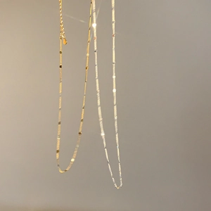 Détail de colliers ras du cou minimalistes en or et argent avec des plaques scintillantes