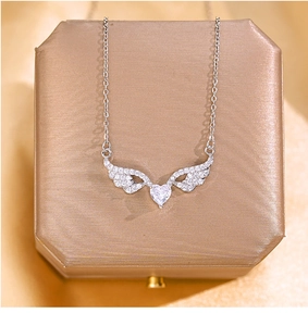 Detail of silver heart wing necklace with zircon crystals on luxury champagne jewelry box