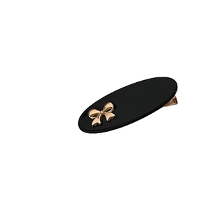 Elegant black oval hair clip with a gold bow accent for minimalist hairstyling