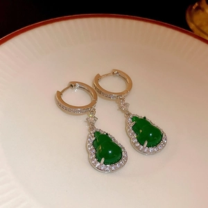 Detailed view of silver drop earrings with green gourd-shaped stone and crystal pavé