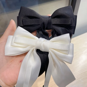 Close-up of black and cream satin bow hair clips with long ribbons in elegant style