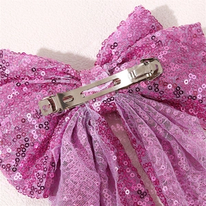 Detail view of pink sequins oversized bow hair clip with silver metal spring fastener