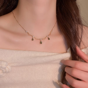 Dettaglio della collana a goccia placcata oro con gemme verdi e zirconi sul collo