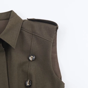Detail of olive green dress with padded shoulders, tortoiseshell buttons and epaulettes