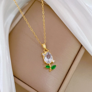 Detailed macro of gold tulip necklace featuring pear-shaped white zircon and green leaves