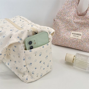 Detailed view of canvas lunch bag side pocket holding a smartphone and zipper closure