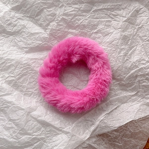 Detail of bright pink faux rabbit fur scrunchie with soft plush texture and high elasticity