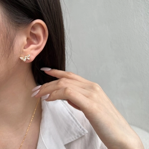 Elegant gold butterfly earrings with white zircon stones on model's ear profile view