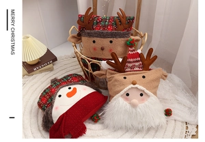 Detailed view of Christmas snowman, reindeer and Santa pillows in a cozy woven basket