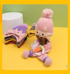 Close-up of knit pink hat with pompom and 3D cartoon rabbit accessory on scarf