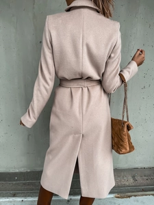 Rear view of long beige wool coat featuring tailored back vent and waist belt