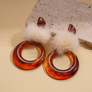 Detailed close-up of amber texture resin hoop earrings with soft white fur pom-poms