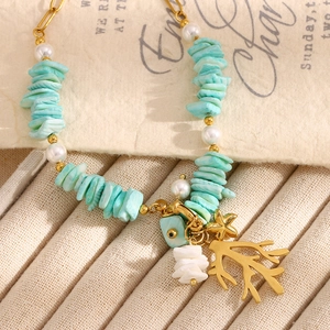Detail of turquoise stone bracelet with coral charm and evil eye bead on gold chain