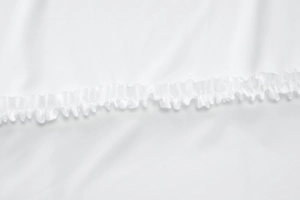 Close-up of white summer dress set showing ruffled edges and smooth fabric texture