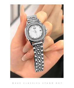 Close-up of diamond-set bezel and white mother-of-pearl dial on a silver steel watch