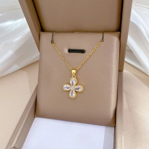Detailed view of a gold clover necklace with four sparkling cubic zirconia in a jewelry box