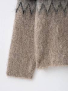 Close-up of fluffy long-pile knit sweater with gray zigzag pattern on camel background