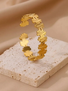 Détail du bracelet ouvert en acier plaqué or 18K avec motifs papillon et gravures