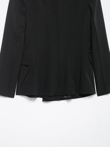 Detailed view of black blazer showing hemline, waist tailoring and side pocket design