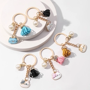 Detailed view of five colorful cat tassel keychains with pearls on a white geometric stand