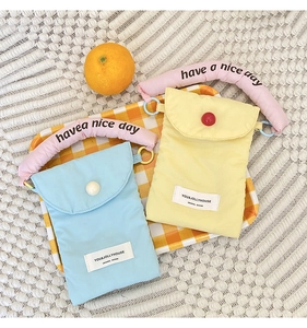 Detail of portable fabric phone bags in blue and yellow with 'have a nice day' handles