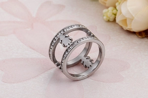 Macro detail of silver double band ring with hollow child figures and pavé rhinestones