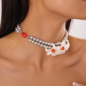 Close-up of double-layer gray pearl necklace with white flower pendants and red beads