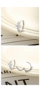 Macro detail of silver cross huggie earrings with zircon inlays and open clasp structure