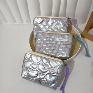 Close-up of silver quilted PU coin purses with heart and checkered patterns in a tray