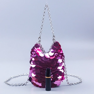 Pink sequin crossbody bag with silver chain strap shown next to lipstick for size
