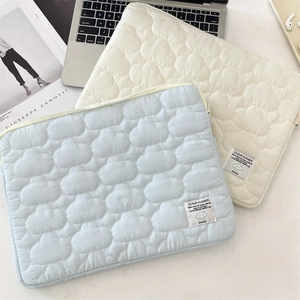 Detail of cloud quilted laptop sleeves in light blue and cream with branded woven labels