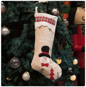 Detail of Christmas snowman stocking with Merry Christmas embroidery on a decorated tree