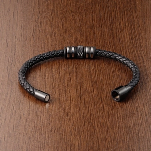Close-up of black braided leather bracelet with magnetic stainless steel clasp on wood