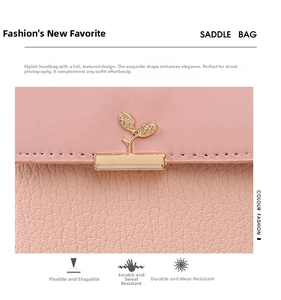 Close-up of pink litchi grain leather saddle bag with a golden leaf-shaped clasp lock