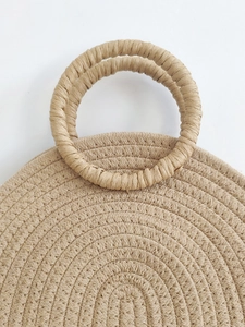 Minimalist woven rattan tote bag featuring a round handle and natural straw fiber texture