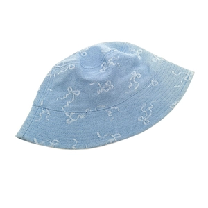 Détail d'un bob en jean bleu clair avec broderies ondulées blanches et coutures renforcées