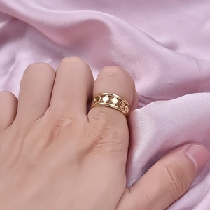 Gold stainless steel ring with hollow circular patterns displayed on pink silk background