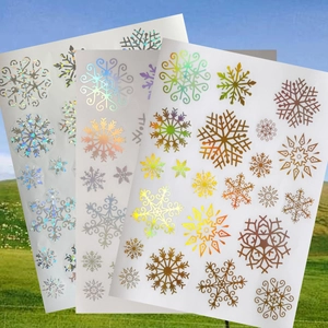 Close-up of three sheets of holographic laser snowflake window stickers with metallic luster