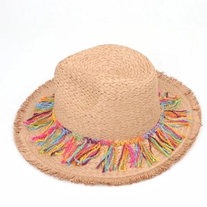 Detail of bohemian straw hat showing colorful yarn tassels and natural fringed brim texture