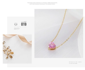 Detalle del colgante de corazón rosa con cadena dorada sobre fondo de seda blanca