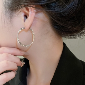 Close-up of silver double-layered textured hoop earrings worn by a model