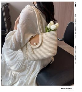 Detail of beige straw handbag with brown pearl flap, lace ribbon and white tulips