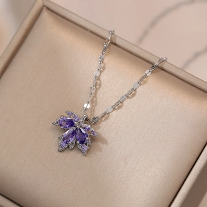 Detailed close-up of purple zircon maple leaf pendant on a silver-tone metal chain necklace