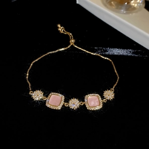 Détail d'un bracelet plaqué or 18k avec pierres carrées roses et breloques en forme d'étoile