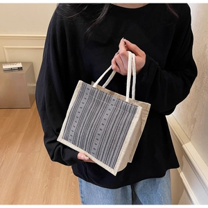 Detailed texture of gray striped linen tote bag with white braided rope handles